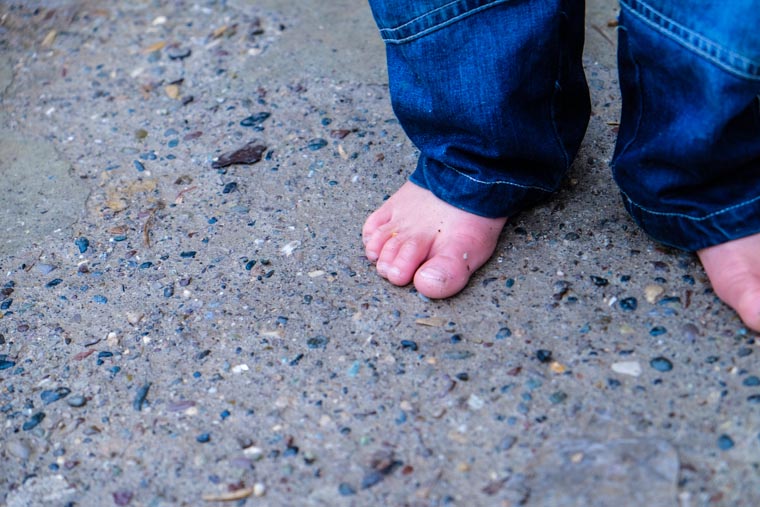 A child in bare feet, standing on cold concrete, before our partners delivered warm boots.
