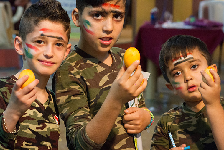 Three boys take a minute to pose for a photo at a recent Easter party, hosted by a local Assyrian church. The boys, dressed in military fatigues and adorned with flag face paintings, hold coloured eggs.
