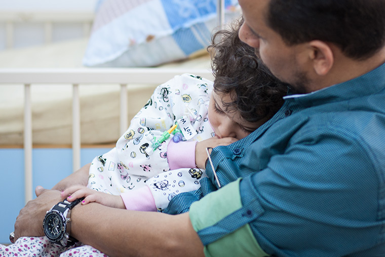 Walla's dad snuggles with her as she rests following her lifesaving heart surgery.