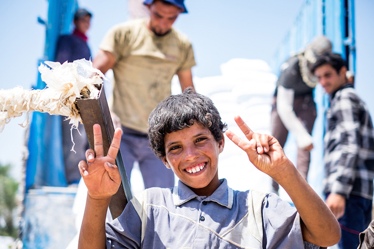 A young teenager stops to pose for a picture. He works long hours hauling a cargo cart, in the Iraqi heat, for little pay.