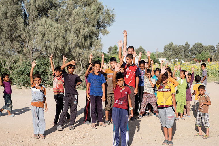 A crowd of displaced kids head off to play soccer with a ball that Emad pulled out of his supplies.