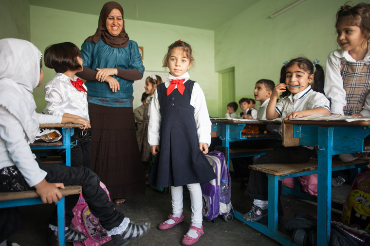 Deeya's teacher stands behind her, her backpack is beside her, and Deeya looks like any other student—as it should be!