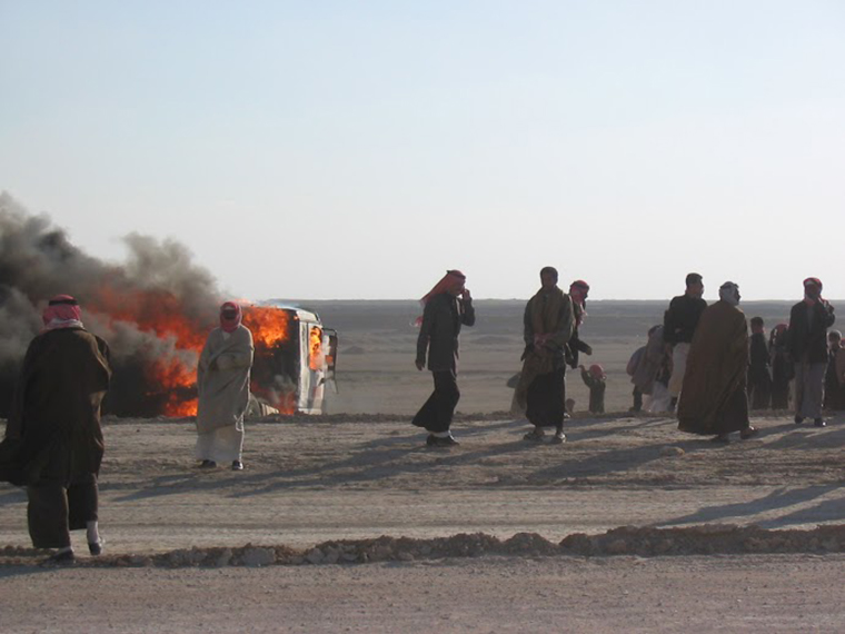A car burns on the side of the road in Iraq, during the US invasion.