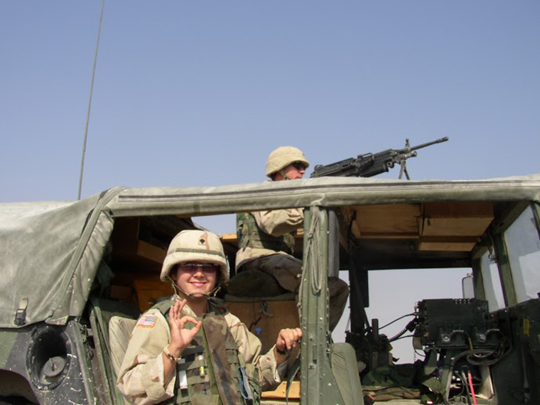 In uniform, Diana takes a minute to smile beside a military vehicle.