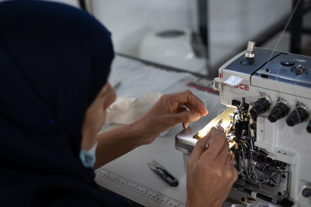 Fatima works at a serger at the maker space sewing studio.